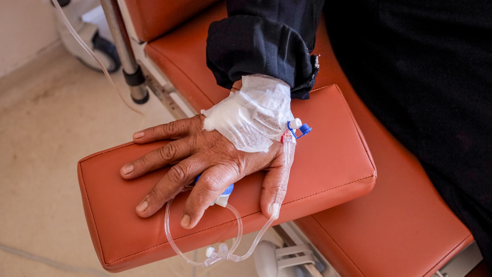 Patient receiving an intravenous infusion through a cannula while resting in a treatment chair